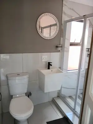 a bathroom with a toilet and a sink and a mirror at De Guest @115 in Centurion