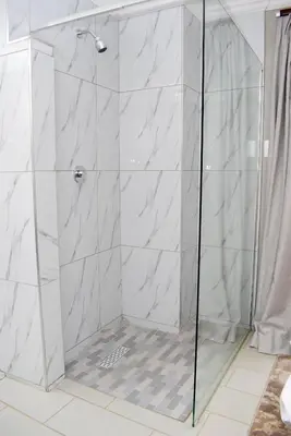 a shower with a glass door in a bathroom at De Guest @115 in Centurion