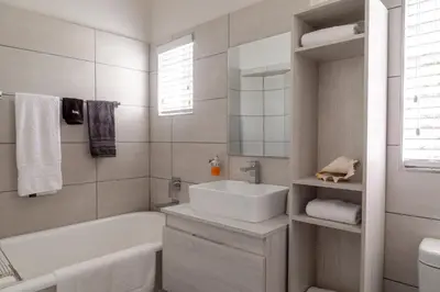 a white bathroom with a sink and a tub and a tubermott at Fig Tree in Pretoria