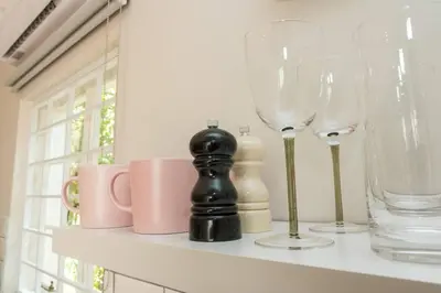 a shelf with wine glasses and mugs on it at Hummingbird in Pretoria