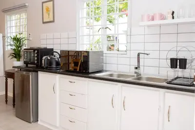 a kitchen with white cabinets and a sink at Hummingbird in Pretoria
