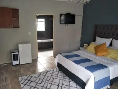 a bedroom with a bed with a blue and white comforter at Serene B&B in Midrand