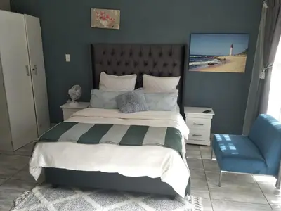 a bedroom with a large bed and a blue chair at Serene B&B in Midrand