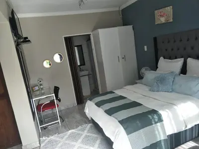 a bedroom with a large bed and a red chair at Serene B&B in Midrand