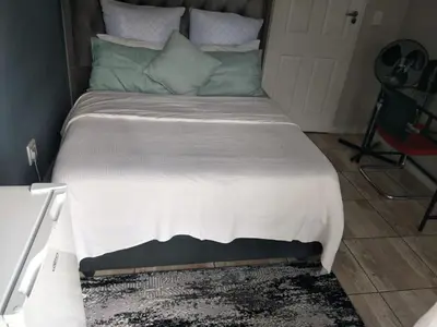 a bedroom with a bed with a white blanket and green pillows at Serene B&B in Midrand
