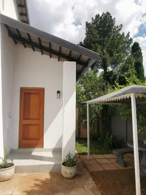 a small white house with a wooden door at Stay@Opstal in Pretoria