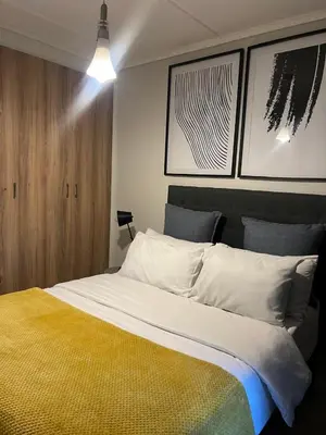a bedroom with a large bed with three pictures on the wall at The Lagoon Exquisite Apartments in Pretoria