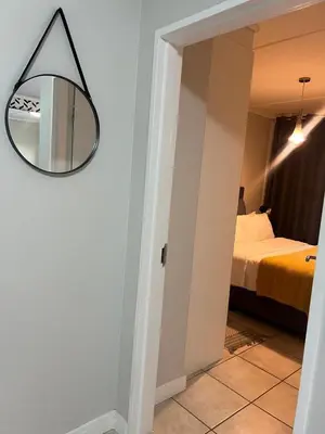 a mirror hanging on a wall next to a bedroom at The Lagoon Exquisite Apartments in Pretoria