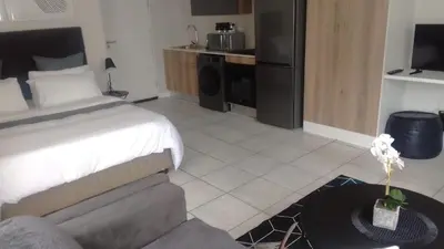 a bedroom with a bed and a couch and a table at The Lagoon Exquisite Apartments in Pretoria