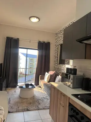 a kitchen with a living room with a couch at The Lagoon Exquisite Apartments in Pretoria