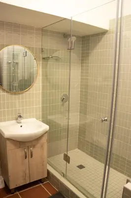 a bathroom with a shower and a sink and a mirror at Grace in Pretoria
