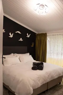 a bedroom with a white bed with birds on the wall at Grace in Pretoria