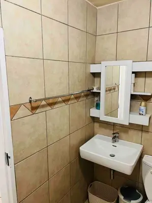 a bathroom with a sink and a mirror and a toilet at Karabo Spaces in Midrand