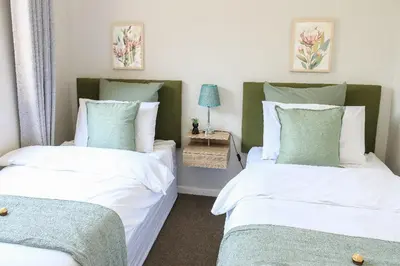 a bedroom with two beds and a table with a lamp at Kirrin Cottage in Benoni in Benoni