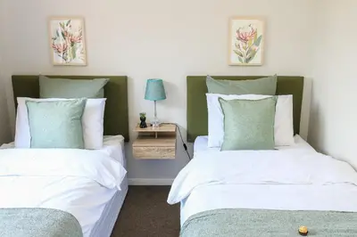 a bedroom with two beds and a table with a lamp at Kirrin Cottage in Benoni in Benoni
