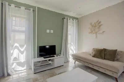 a living room with a couch and a tv at Kirrin Cottage in Benoni in Benoni