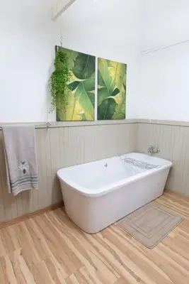 a white bath tub in a bathroom with a wooden floor at Lala Lapa Self Catering Accomodation in Nelspruit