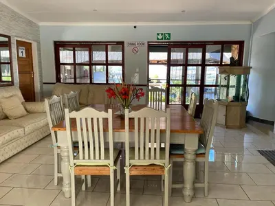 a dining room with a wooden table and chairs at Eagles View Kungwini in Erasmus