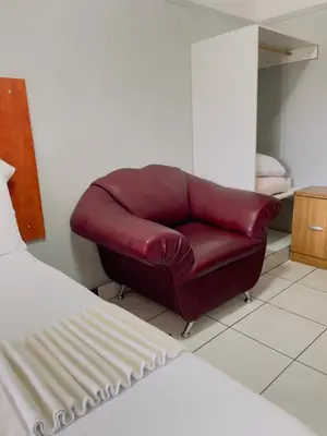 a red leather couch sitting in a bedroom at Sunrise Guest Inn in Pretoria