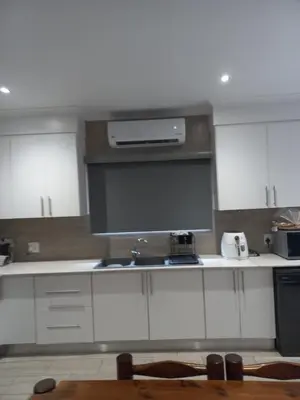 a kitchen with white cabinets and a sink at Woodlands on Korhaan 2926 in Marloth Park