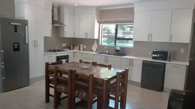 a kitchen with a table and chairs and a refrigerator at Woodlands on Korhaan 2926 in Marloth Park