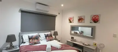 a bedroom with a bed with a large headboard and a mirror at Woodlands on Korhaan 2926 in Marloth Park