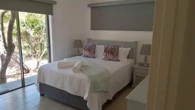 a bedroom with a bed and a large window at Woodlands on Korhaan 2926 in Marloth Park