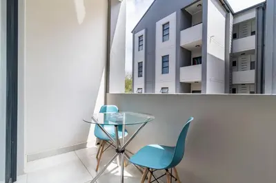 a glass table and chairs in a room with a window at The Ace apartment @50 on lever(with backup power) in Midrand