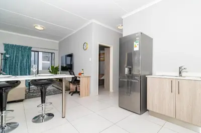 a kitchen with a stainless steel refrigerator and a table at The Ace apartment @50 on lever(with backup power) in Midrand
