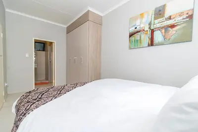 a bedroom with a white bed and a painting on the wall at The Ace apartment @50 on lever(with backup power) in Midrand