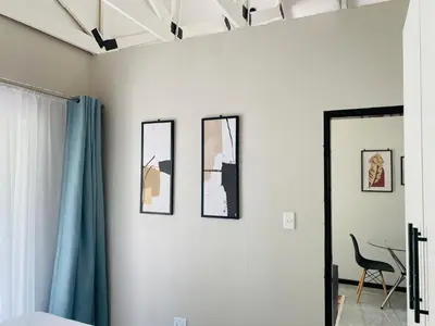 a room with four pictures on the wall and a chair at Cozy Garden Facing Guest Suite -(Back up power) in Midrand