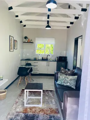 a living room with a couch and a table at Cozy Garden Facing Guest Suite -(Back up power) in Midrand