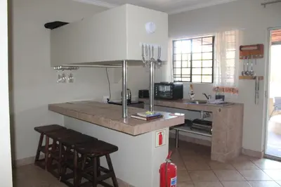 a kitchen with a counter and two stools in it at Kruger Bush Retreat in Marloth Park