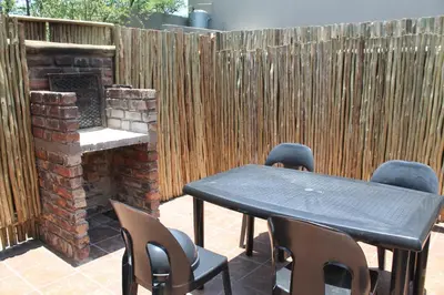 a patio with a table and chairs and a brick fireplace at Kruger Bush Retreat in Marloth Park