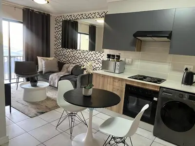 a kitchen and living room with a table and chairs at The Green Lifestyle Apartments in Pretoria