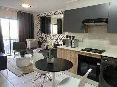 a kitchen and living room with a table and a couch at The Green Lifestyle Apartments in Pretoria