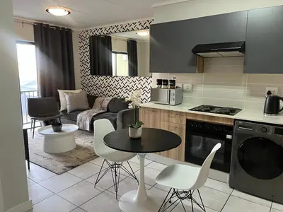 a kitchen and living room with a table and chairs at The Green Lifestyle Apartments in Pretoria