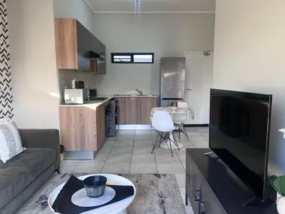 a living room with a couch and a kitchen at The Green Lifestyle Apartments in Pretoria