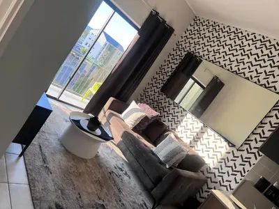 a living room with a couch and a mirror at The Green Lifestyle Apartments in Pretoria