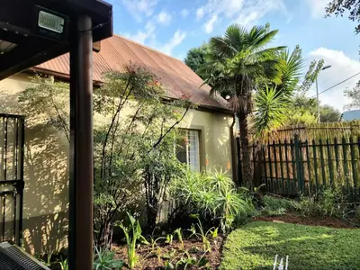 a house with a fence and a palm tree at Selah, self-catering in Pretoria