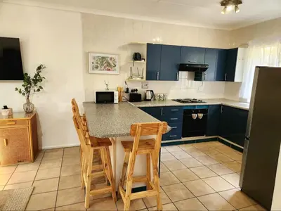 a kitchen with blue cabinets and a table and chairs at Selah, self-catering in Pretoria