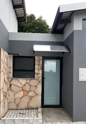 a house with a glass door and a stone wall at Mulala Luxury Guesthouse in Thohoyandou