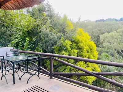a balcony with a table and a view of trees at Pretoria Mansion Boutique Hotel Coral Tree in Pretoria