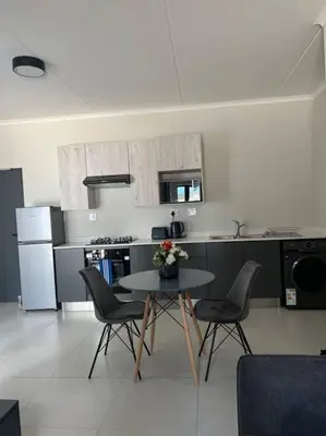 a kitchen with a table and chairs in a room at Liams blue suite at 93 On New in Midrand