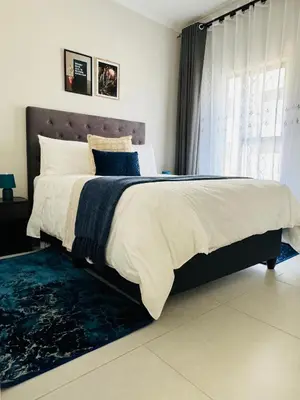 a bedroom with a large bed with a blue rug at Liams blue suite at 93 On New in Midrand