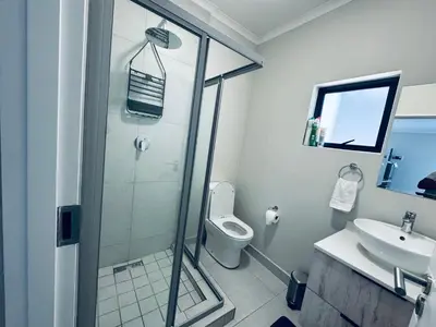 a bathroom with a shower and a toilet and a sink at Liams blue suite at 93 On New in Midrand