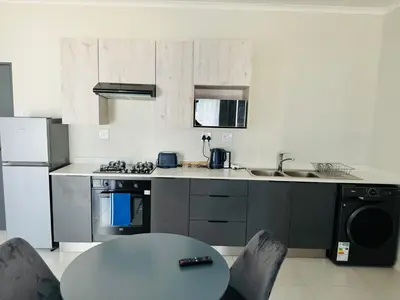 a kitchen with a table and a stove and a sink at Liams blue suite at 93 On New in Midrand