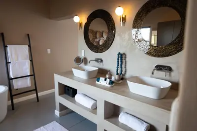 a bathroom with two sinks and two mirrors at Marepe Mountain View in Kampersrus AH