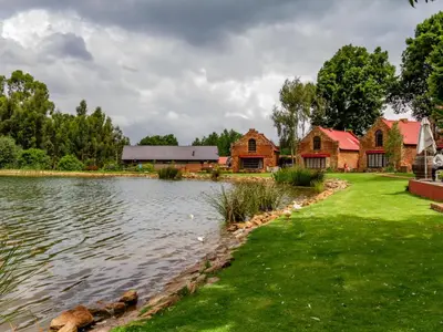 a pond in front of a farm with buildings at Critchley Hackle Lodge in Dullstroom
