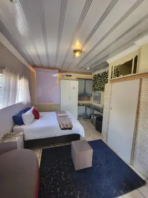 a small room with a bed and a kitchen at Tshedza Guest House in Pretoria